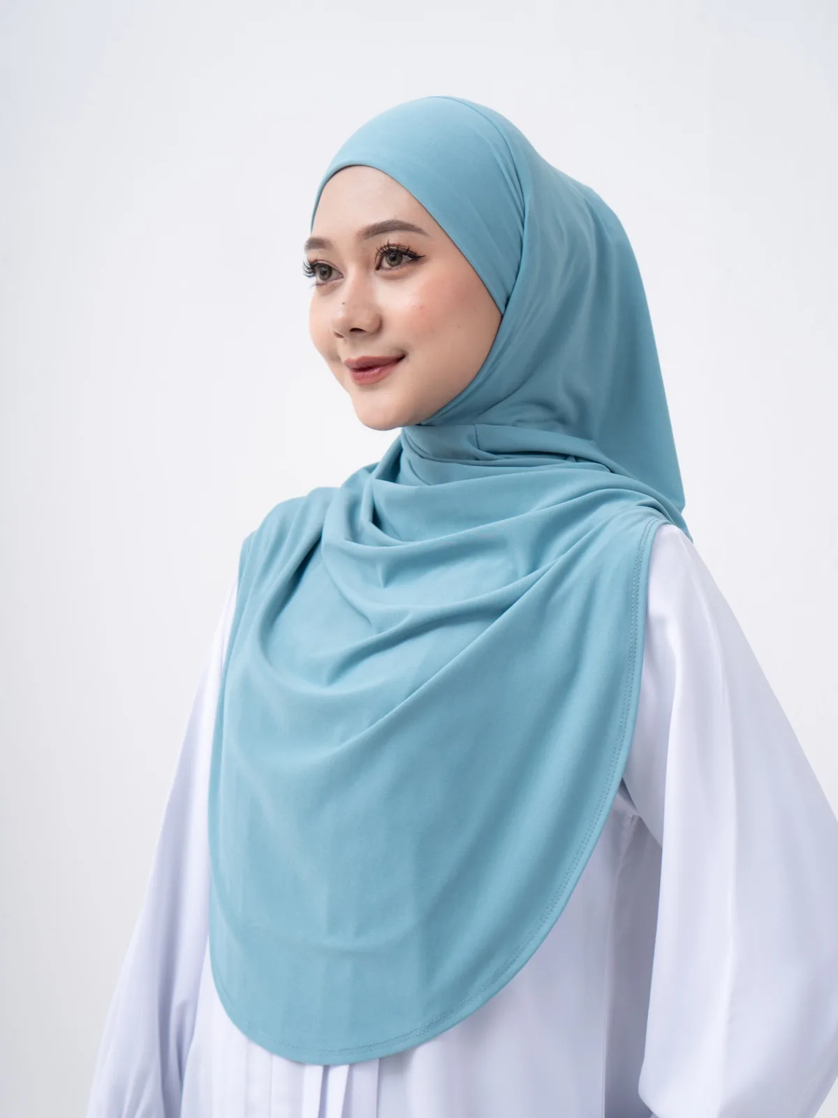 A woman wearing a SONA hijab in turquoise with a white top